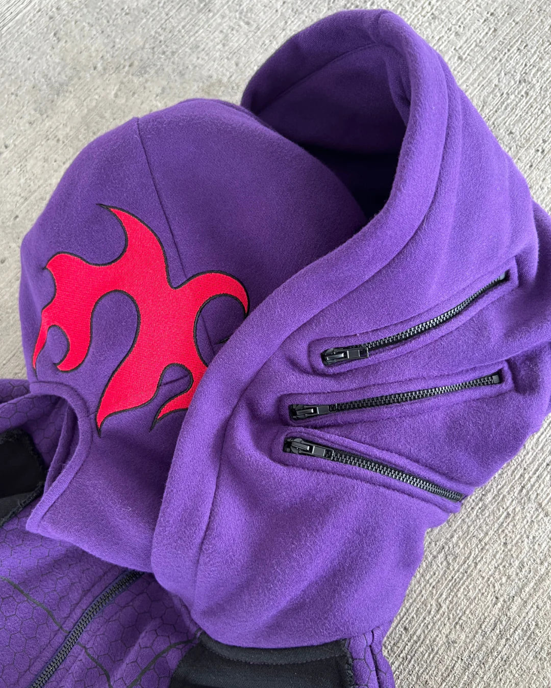 Purple hoodie with a red flame design on a gray surface